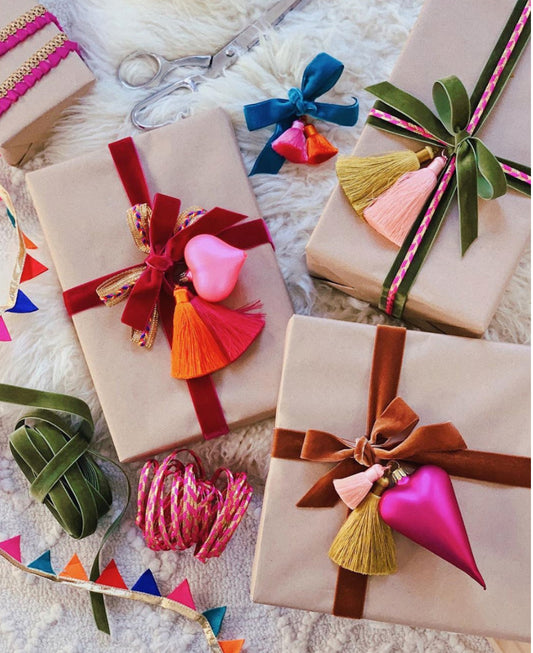 A photo of pretty wrapped gifts in Kraft paper and beautiful colorful ribbon and colorful tassels 